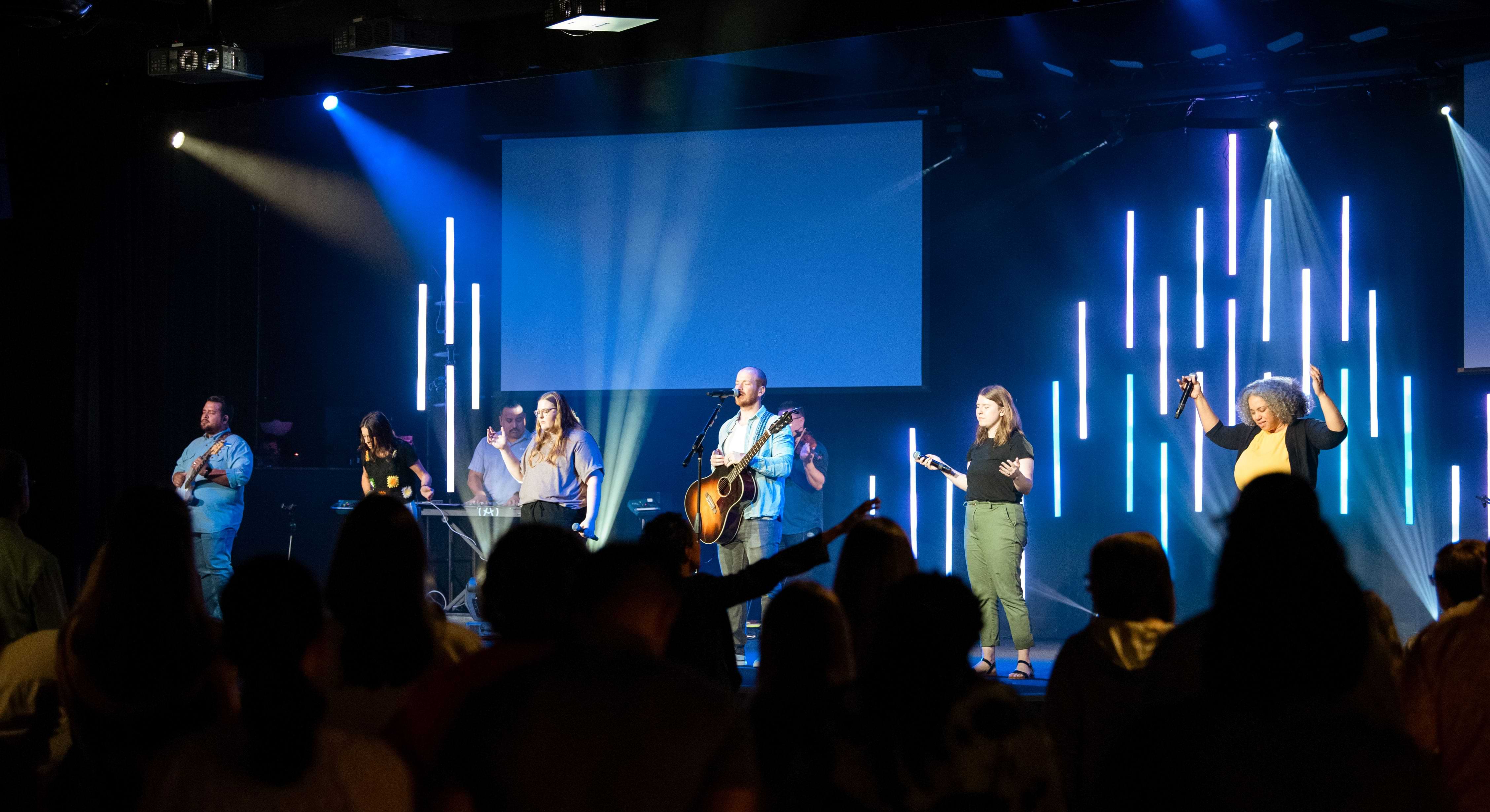 Crowd of people in worship with a band on stage