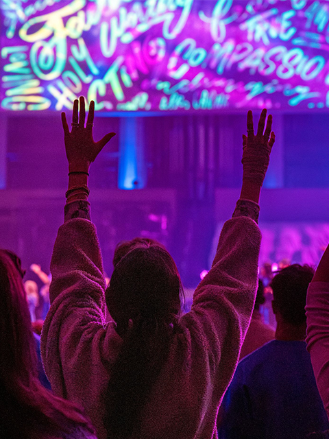 Woman with her hands up in praise in a crowd